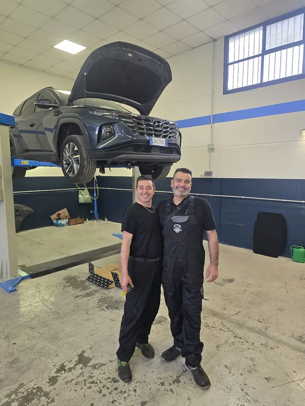 Il team di Tano Evoluzione davanti a un'auto sul ponte sollevatore